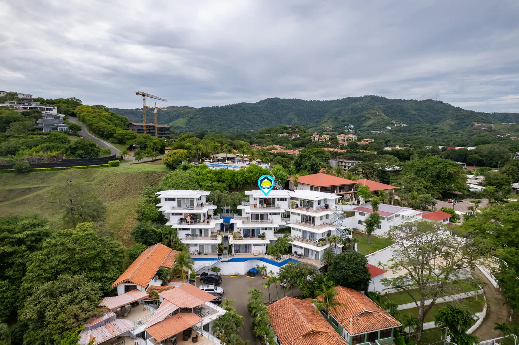 Shared amenity: Aerial view of a resort complex among green hills and trees.