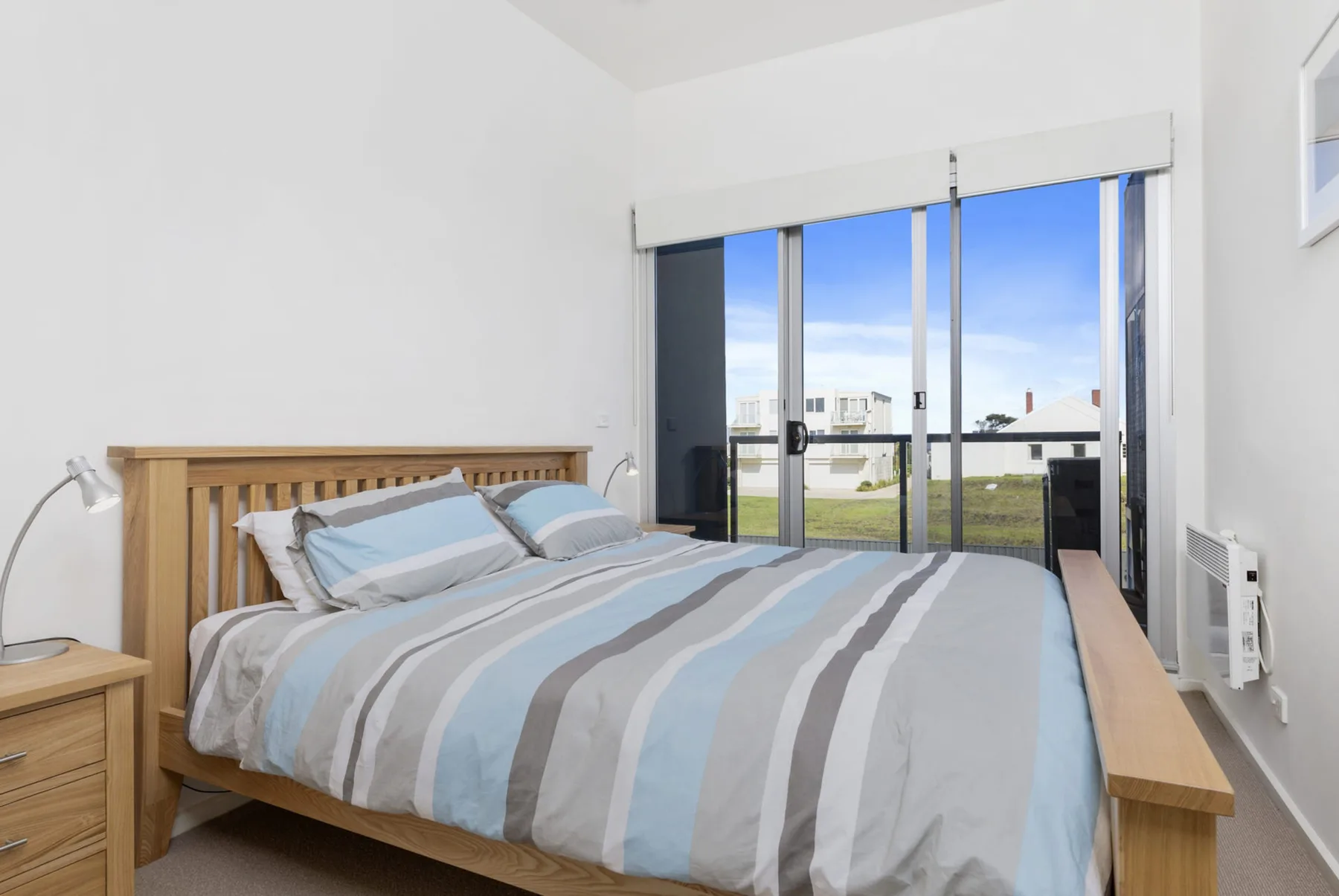 Un dormitorio con una cama de madera y puertas corredizas de vidrio que dan a un balcón.