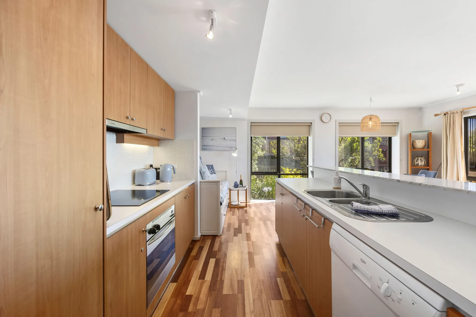 Una cocina luminosa con gabinetes de madera, una isla central y ventanas con vistas a la vegetación.