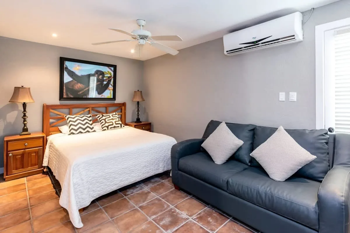 A bedroom with a bed and a dark sofa beside it.