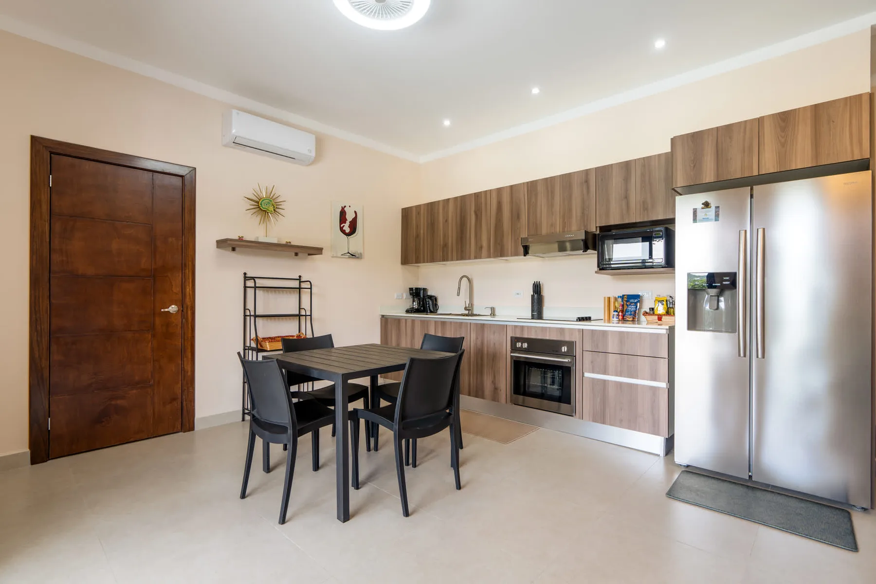 A kitchen and dining area with a table, dark seating, and stainless-steel appliances.