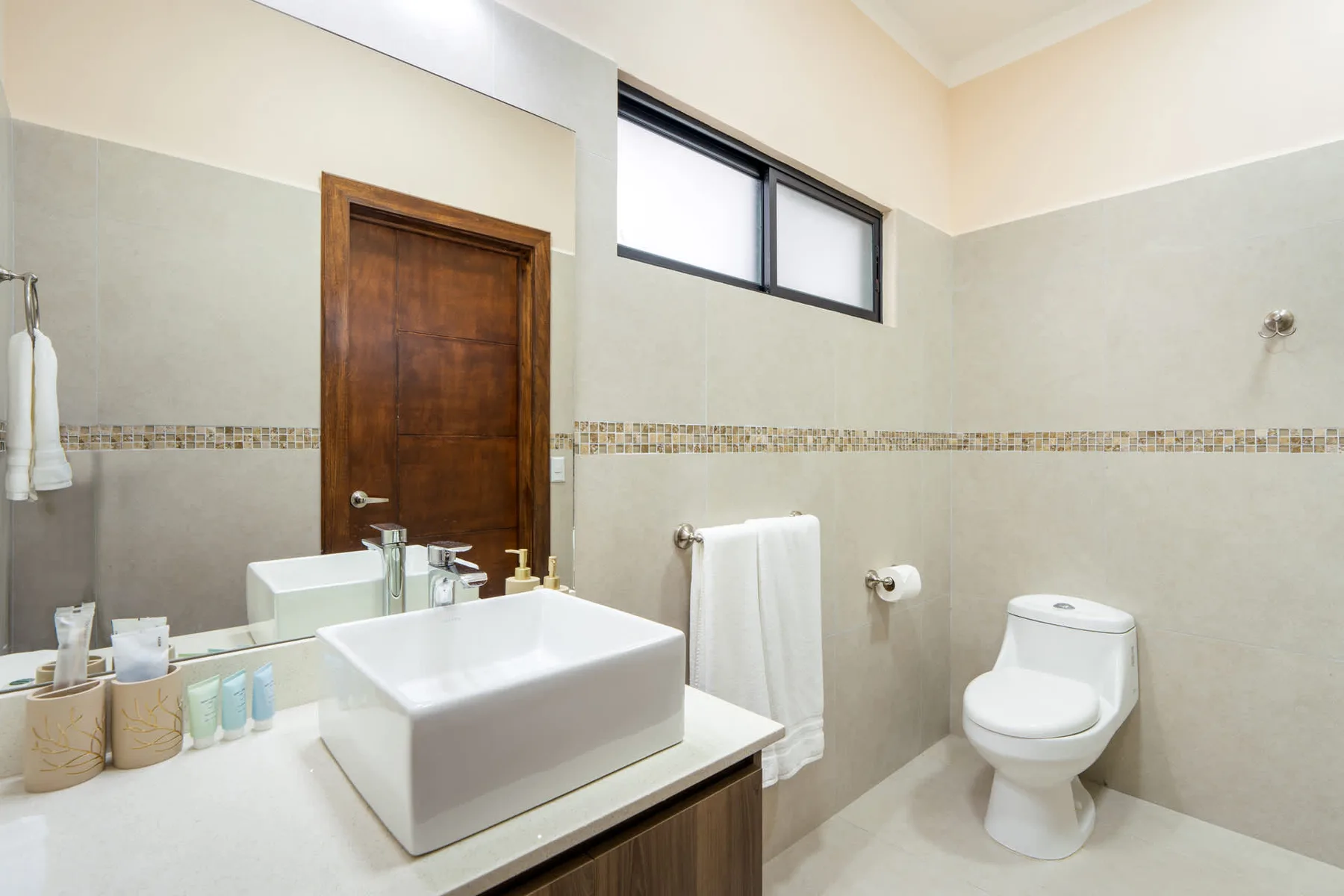 A bathroom with a sink, toilet, and towel beside a wooden door.