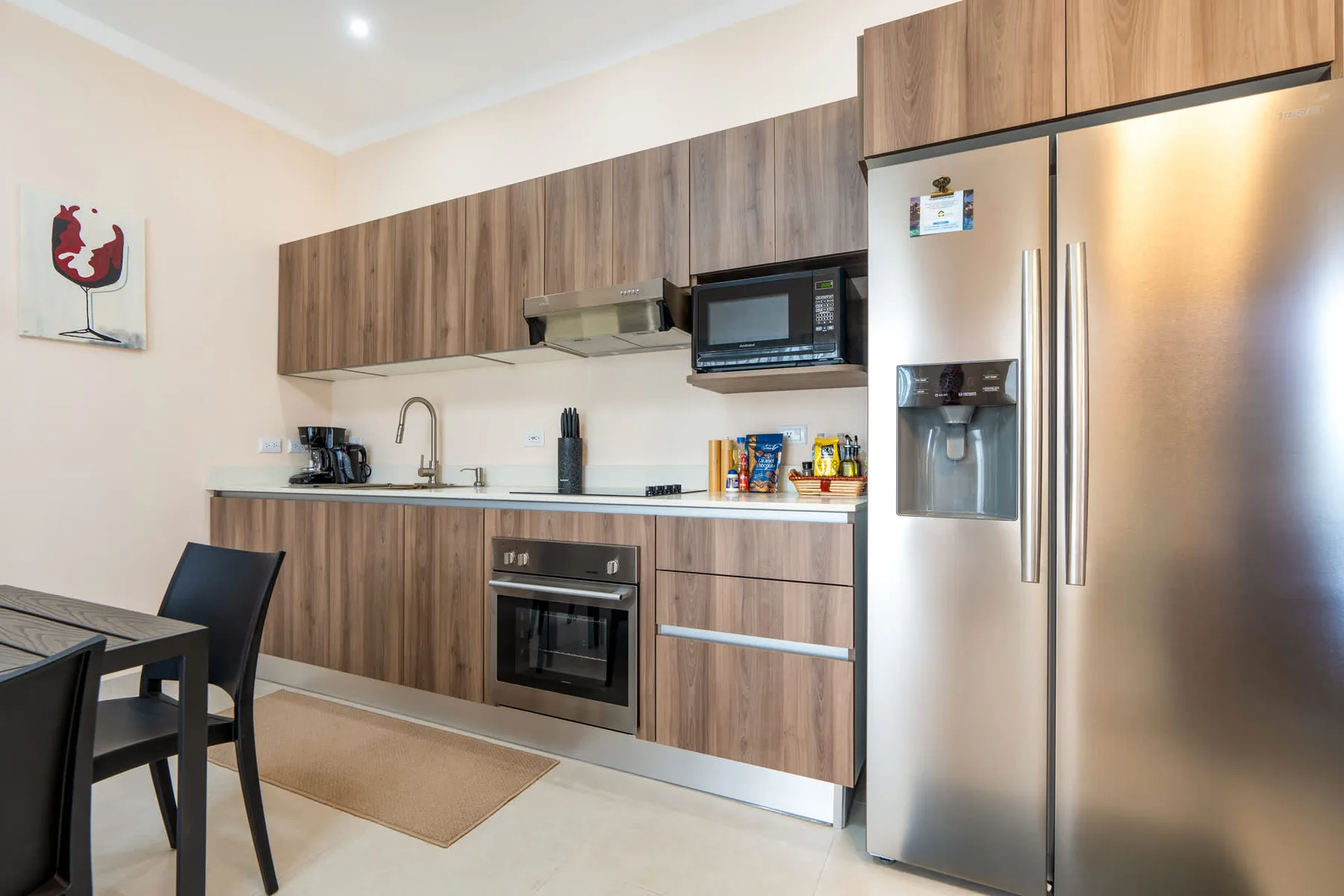 A modern kitchen with wood cabinets, stainless steel appliances, and a dining table.