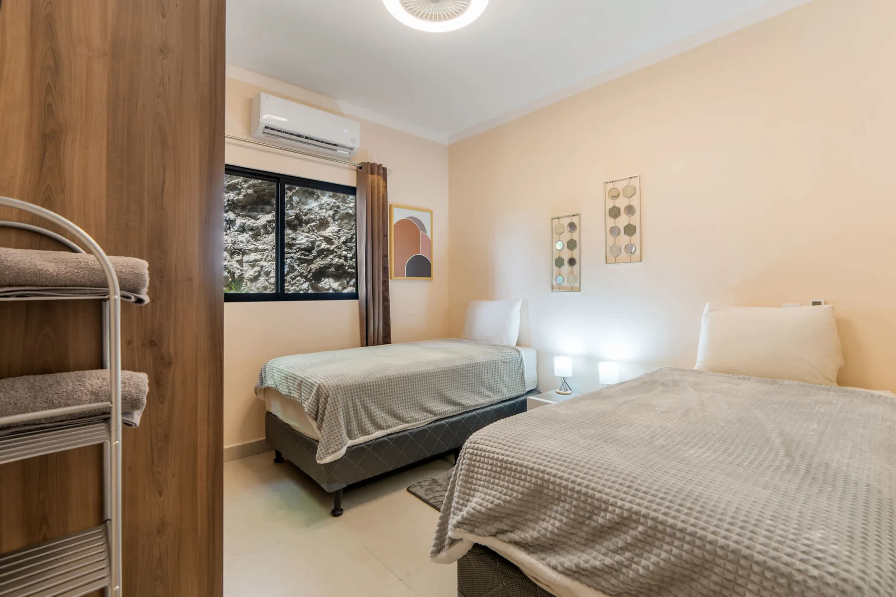 A bedroom with two beds, a window, and framed wall art.