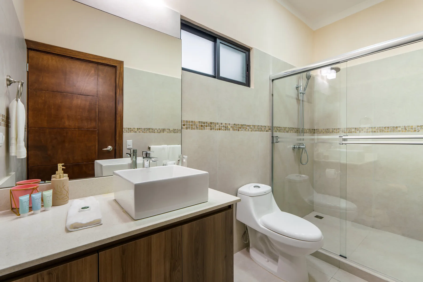 A bathroom with a vanity, toilet, and glass-enclosed shower.