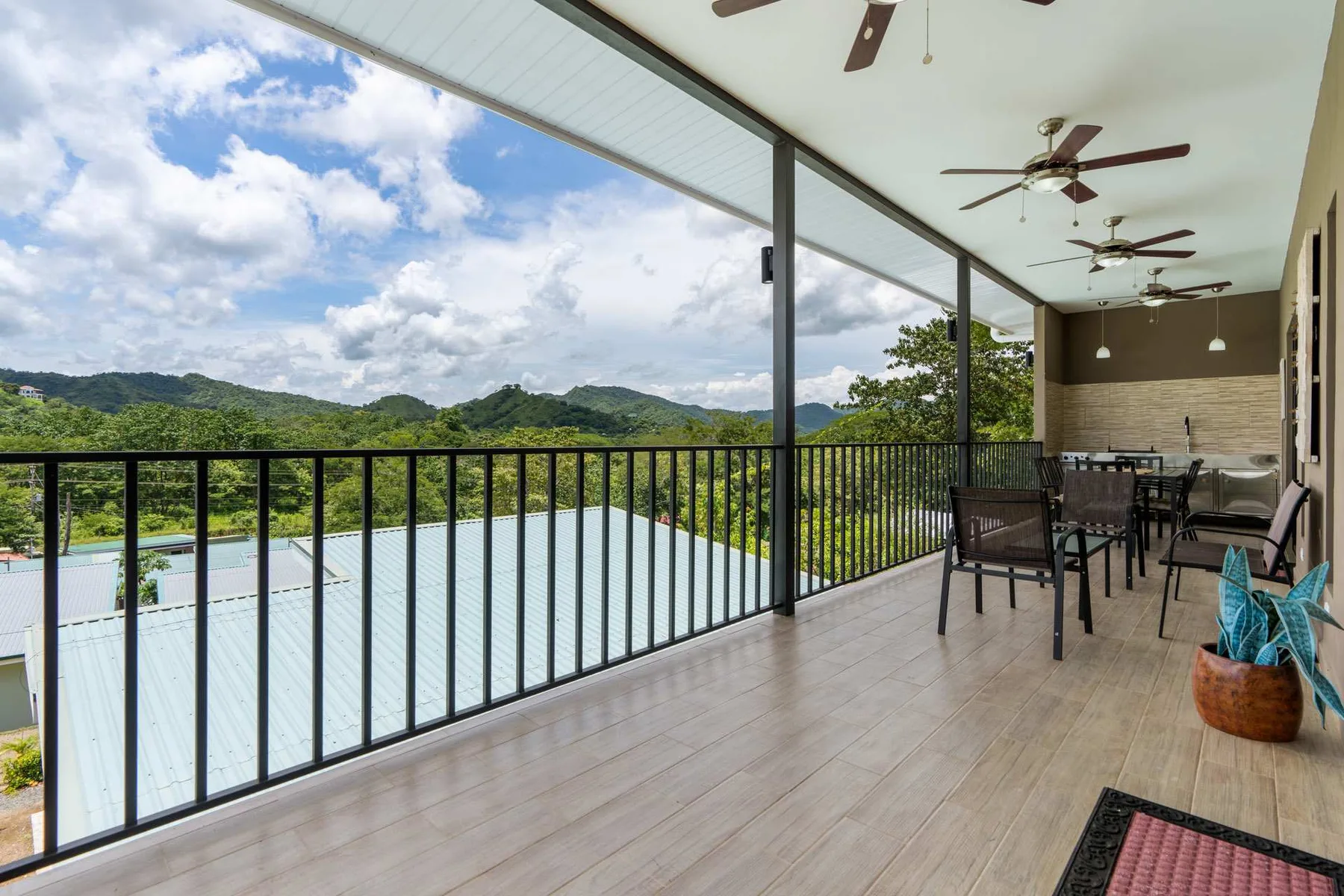 A covered outdoor dining area overlooks green hills and rooftops.