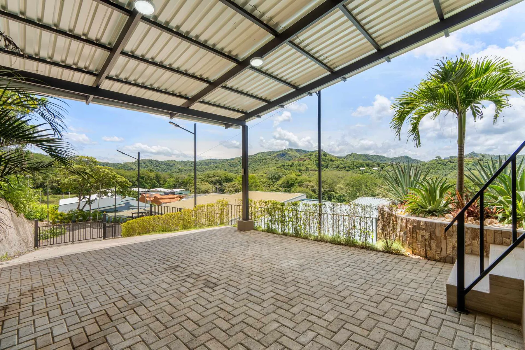 A covered outdoor patio overlooks green hills and a valley.