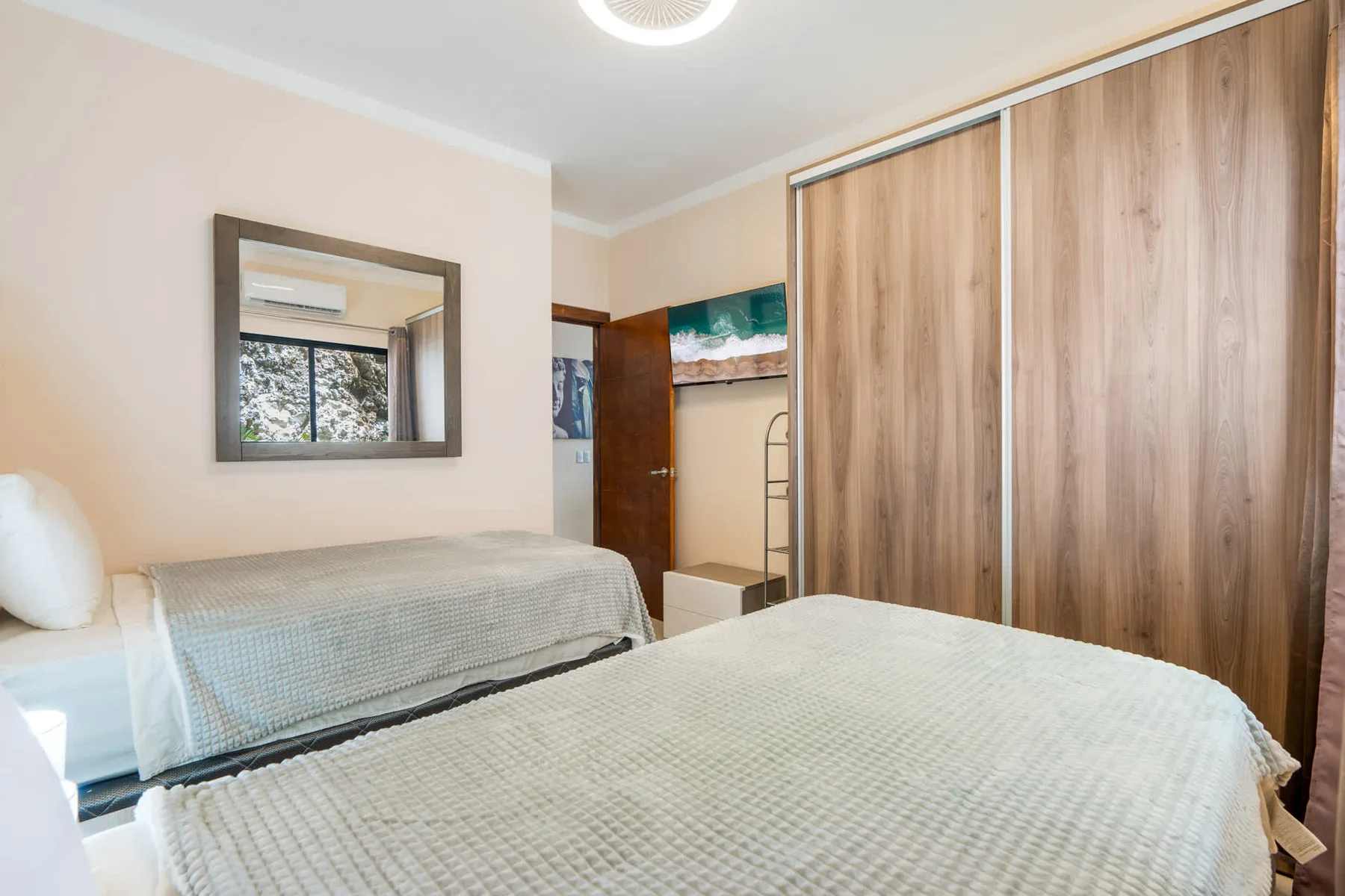 A bedroom with two beds and a large wood-toned wardrobe.