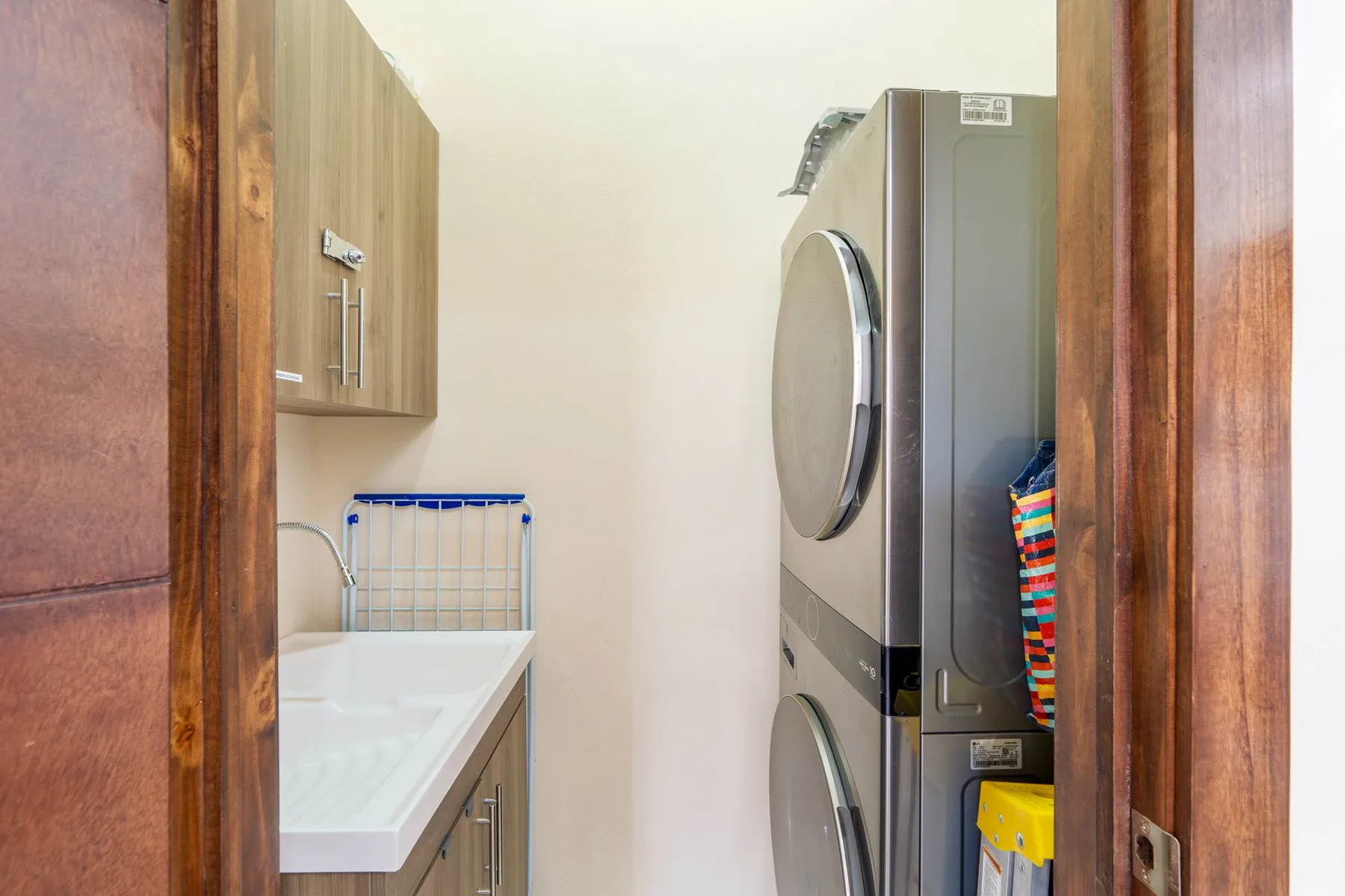 A compact laundry area has stacked laundry machines beside a utility sink.