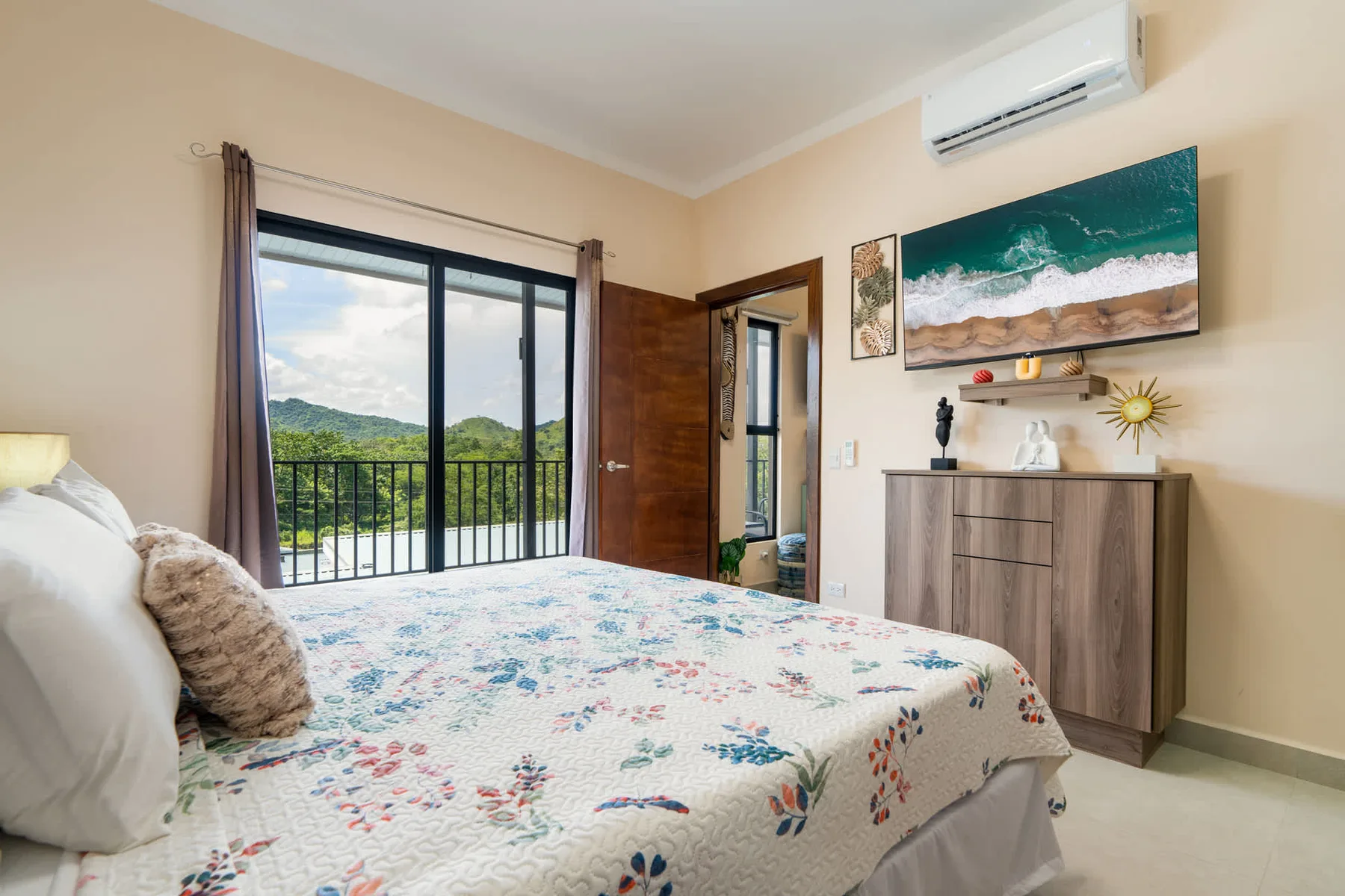A bedroom with a floral bedspread, sliding glass doors, and wall art.