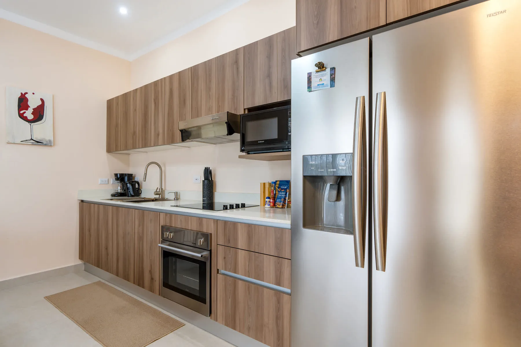 A modern kitchen with wood cabinetry, a cooktop, and stainless steel appliances.