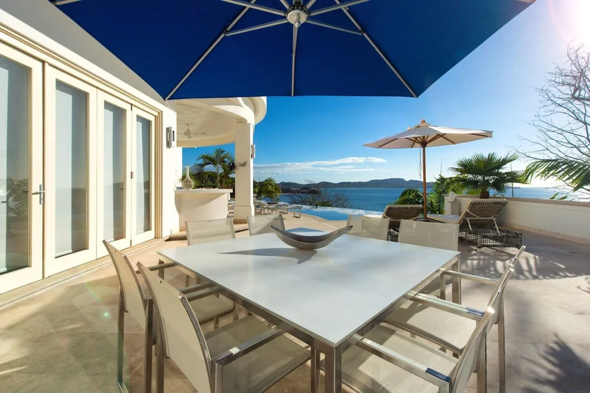 An outdoor dining area with a table and seating overlooking the water.