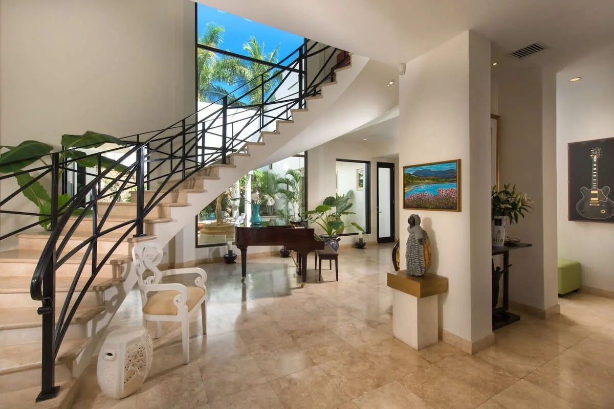 A bright interior living area with a staircase, seating, and plants.