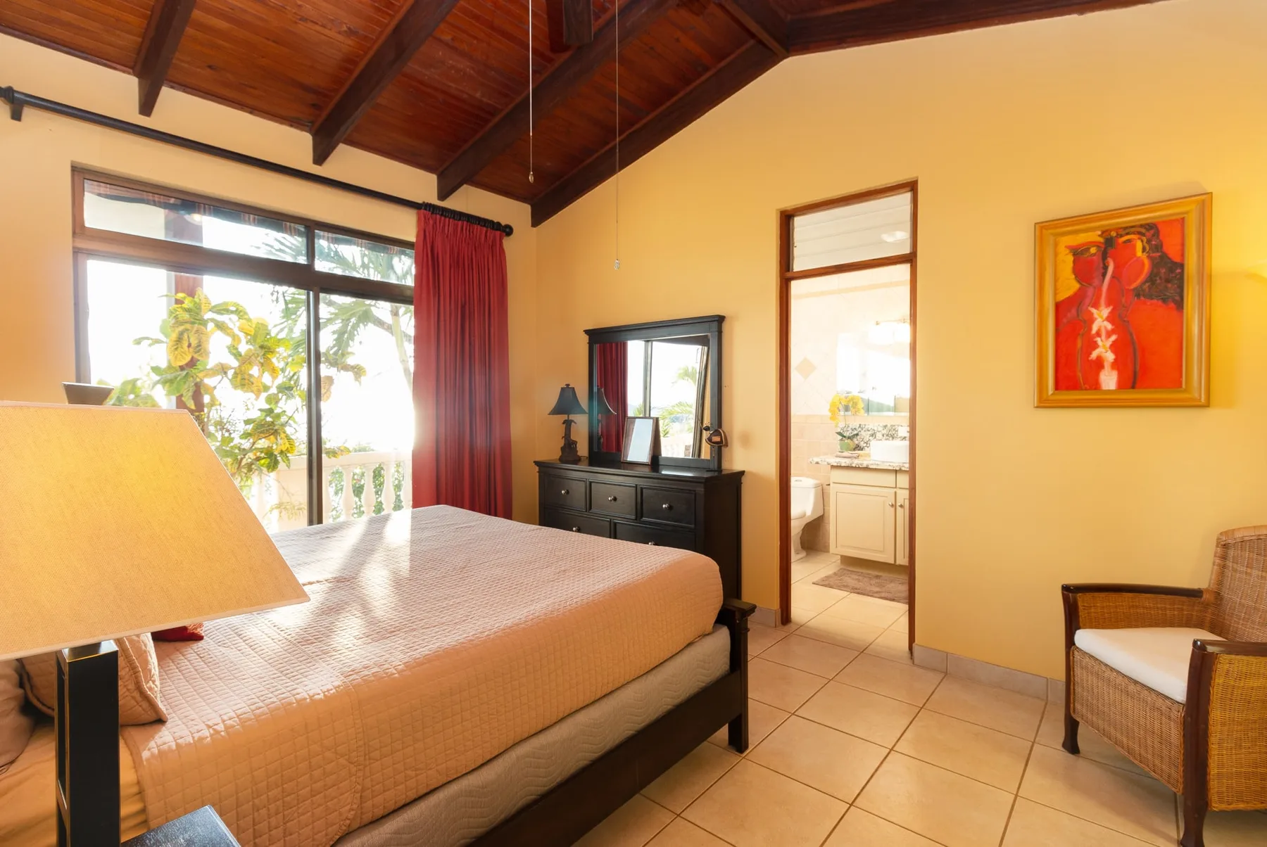 A bedroom with a bed, a window, and a doorway to the bathroom.