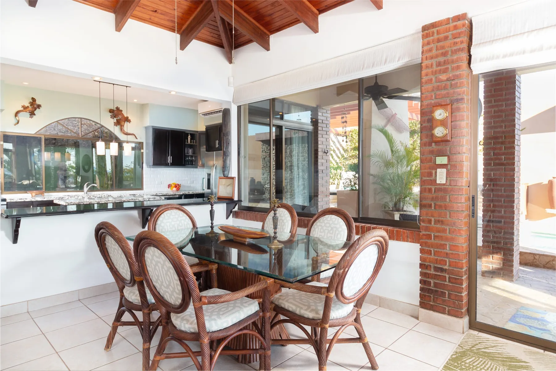 A dining area with a glass table and wicker seating beside the kitchen.