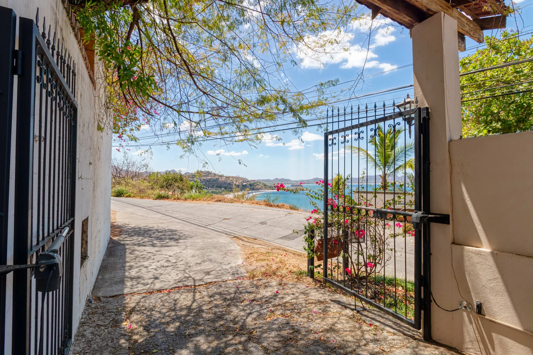 An open garden gate leads to a paved path overlooking the water.