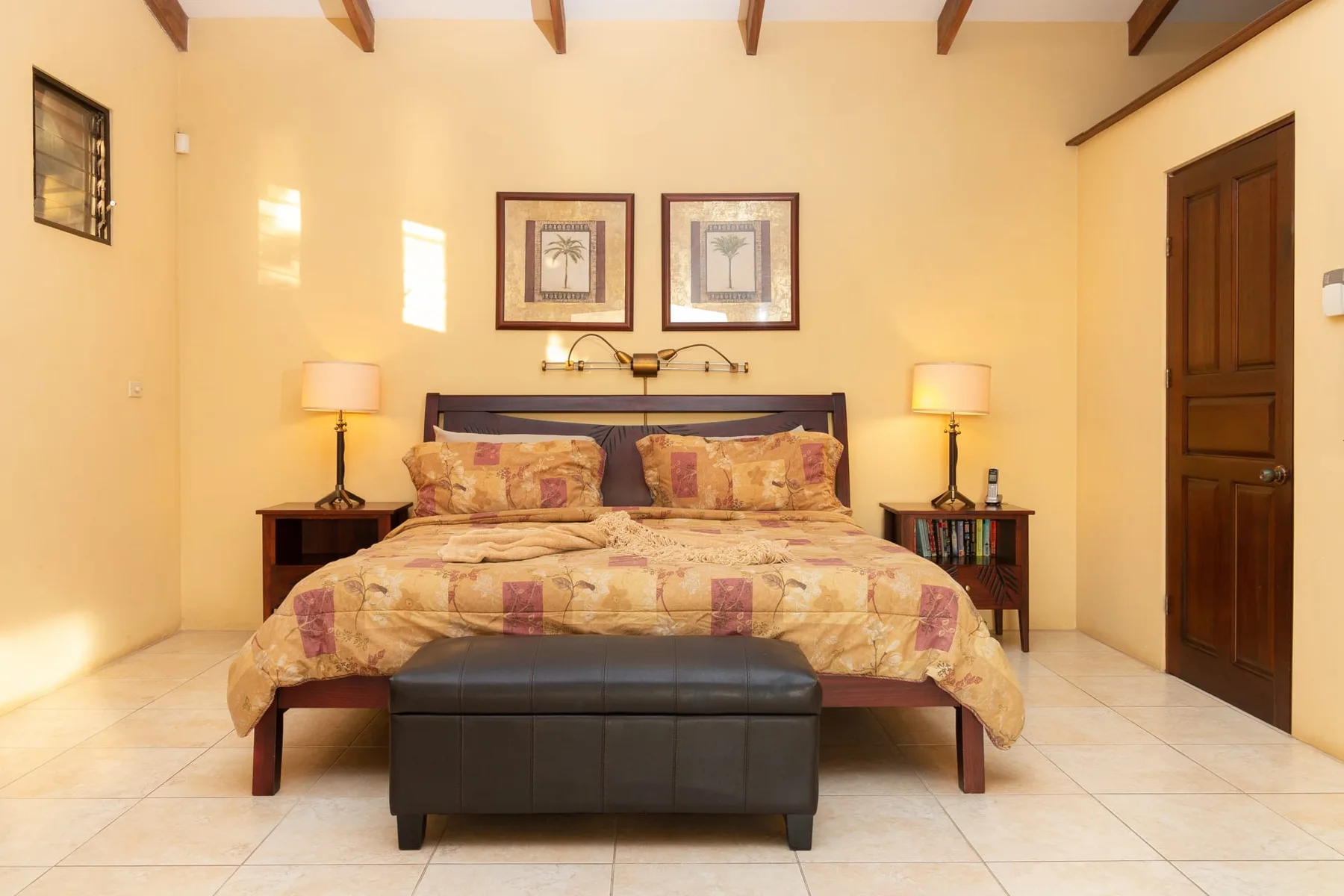 A bedroom with a bed, matching bedside tables, and framed artwork above the headboard.