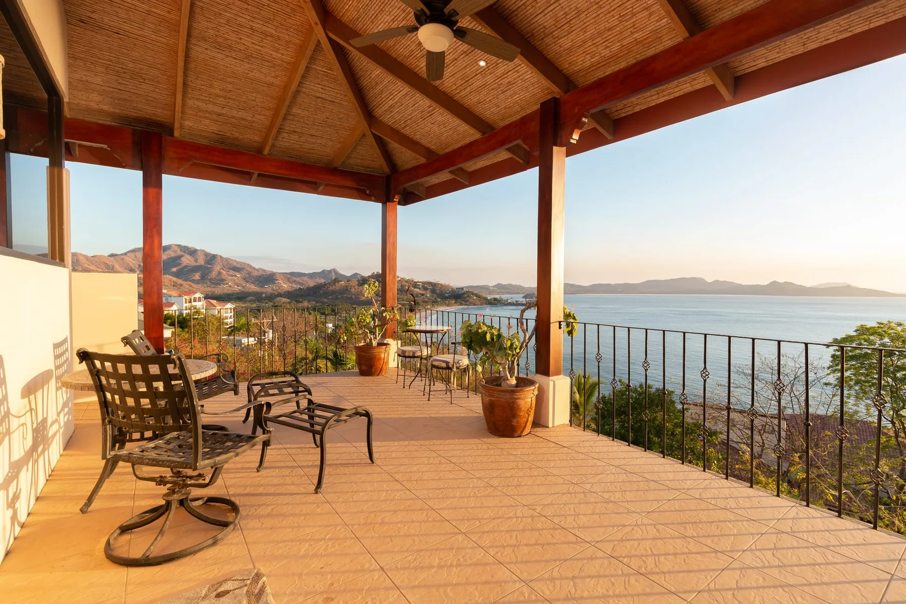 A covered terrace overlooks the water, with outdoor seating and potted plants.