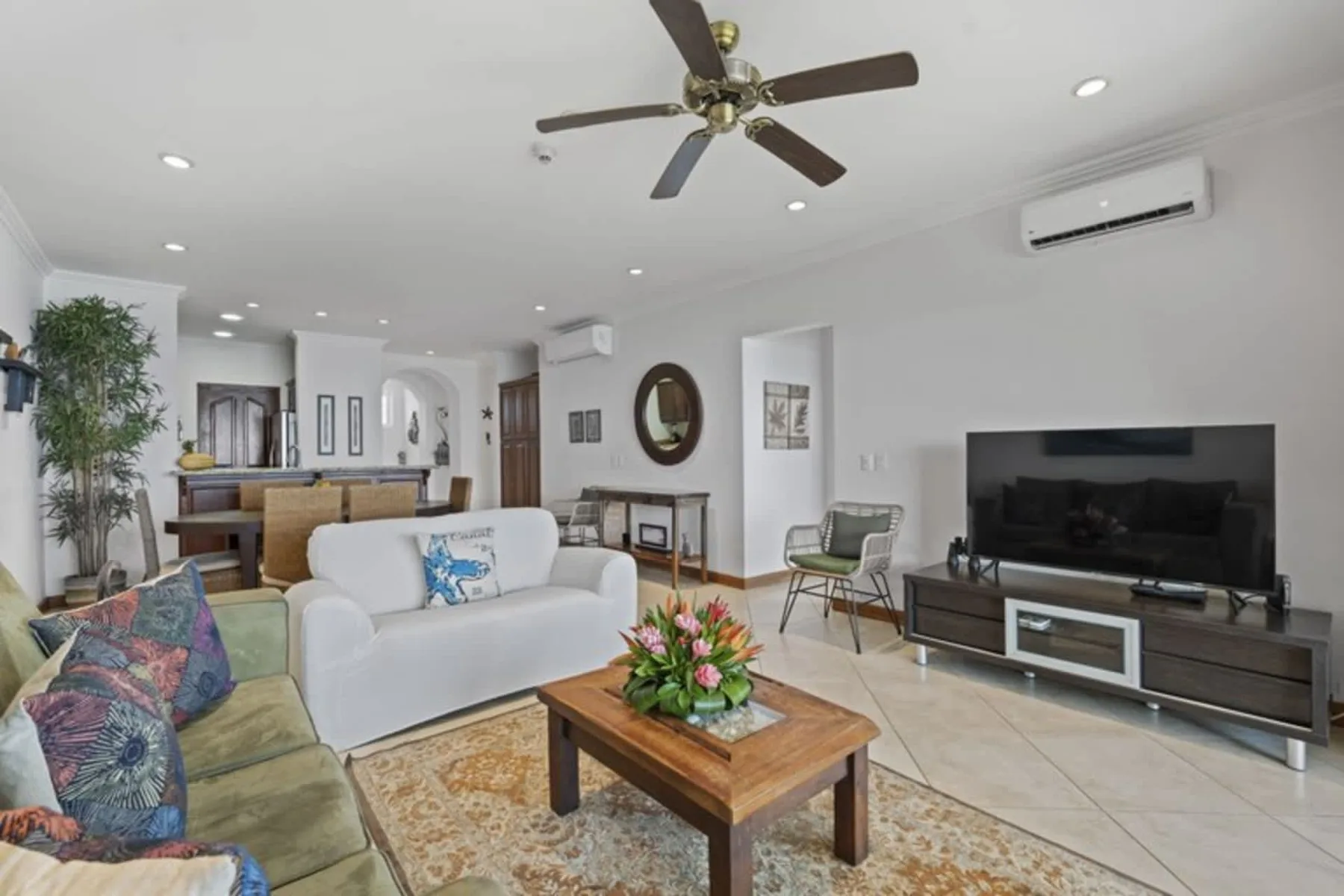 A bright living room with seating, a television, and a wooden coffee table.