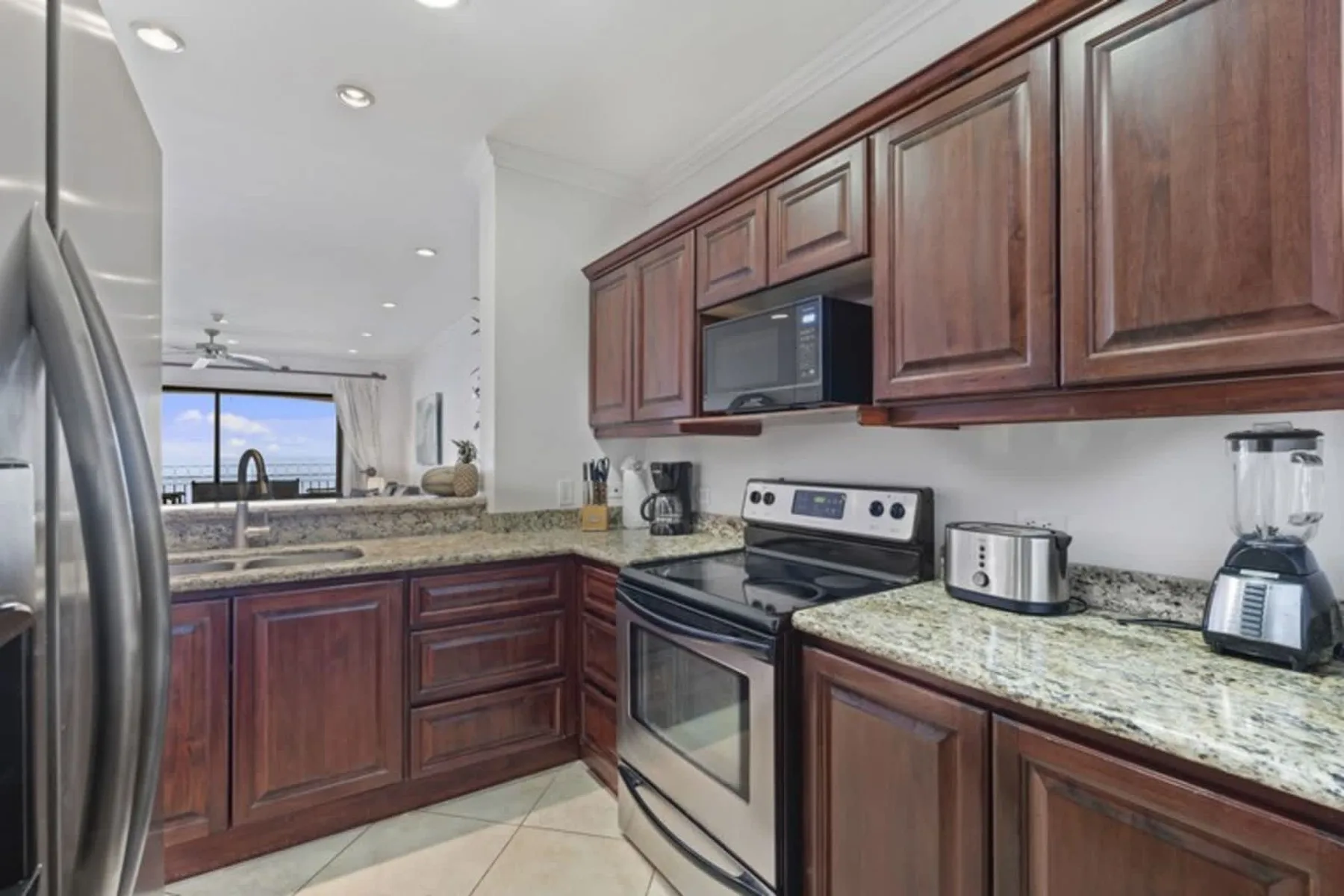 A kitchen with dark wood cabinets, stone countertops, and stainless steel appliances.