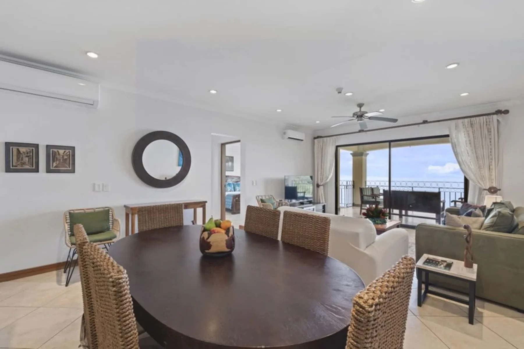 A bright living and dining area opens onto a balcony through wide glass doors.