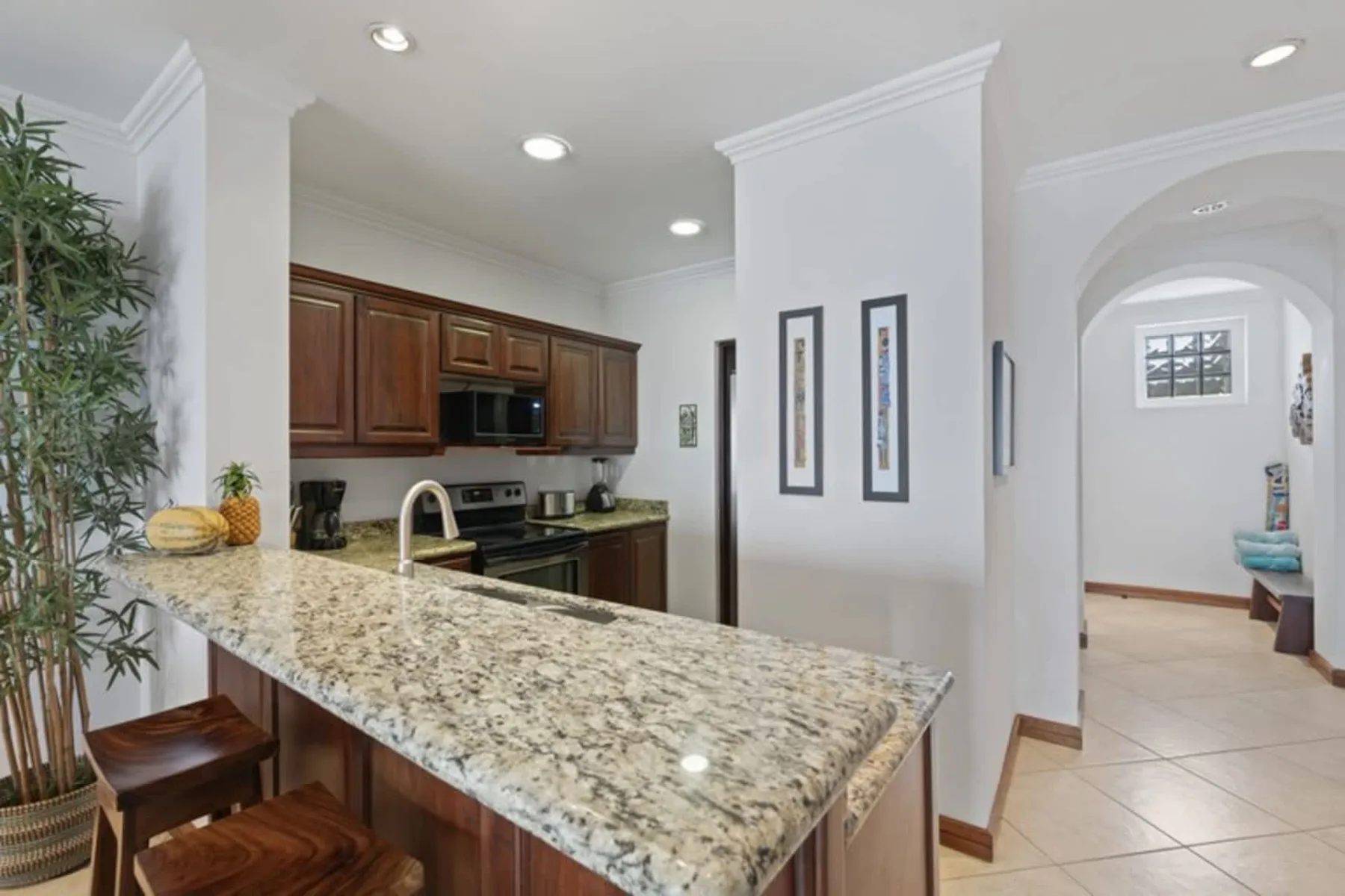 A kitchen with dark wood cabinets and a long granite countertop.
