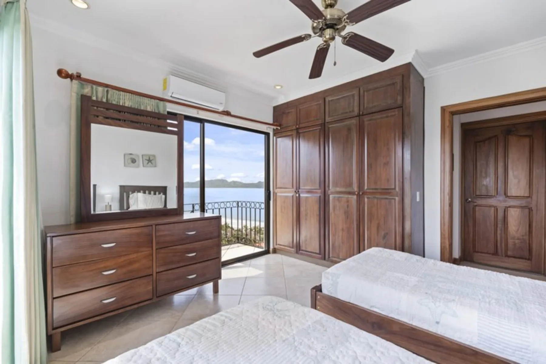 A bedroom with wooden furnishings and a sliding glass door opening to a balcony.