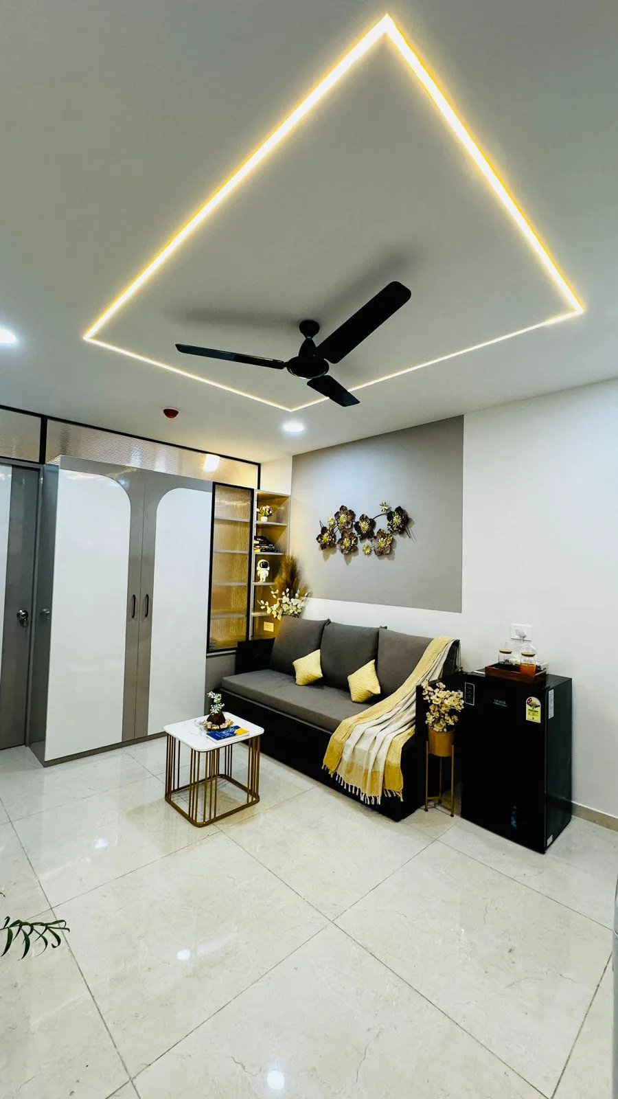 A compact living room with a dark sofa, a small coffee table, and ceiling lighting.