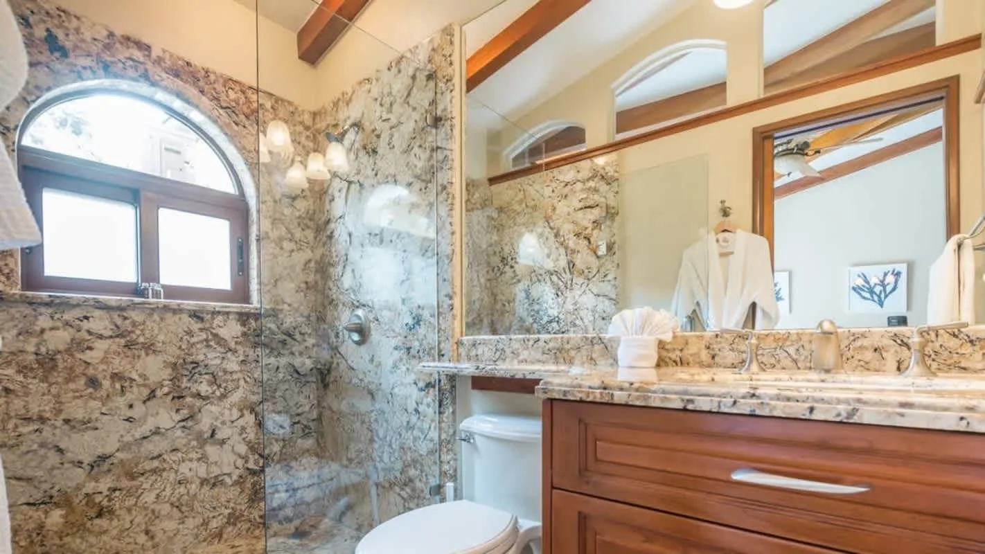 A bathroom with a marble-patterned shower area and a long vanity.