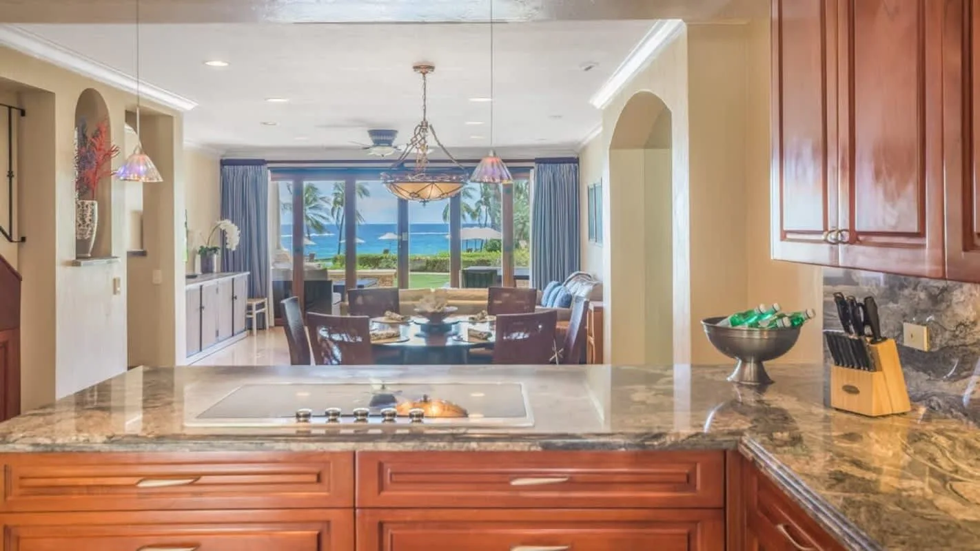 A kitchen opens onto a dining area with large windows overlooking the water.