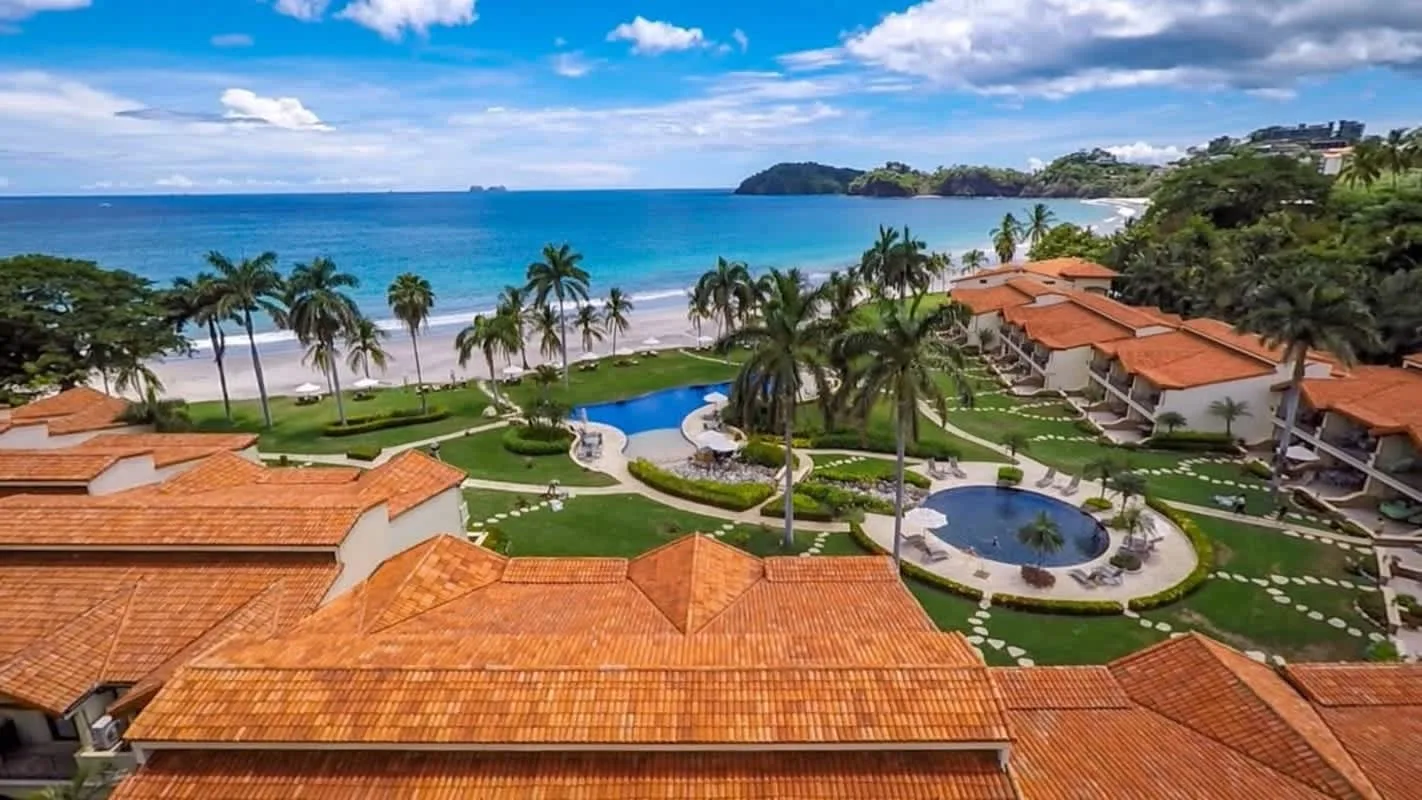 Shared amenity: Aerial view of a beachfront resort with terracotta roofs and a swimming pool.