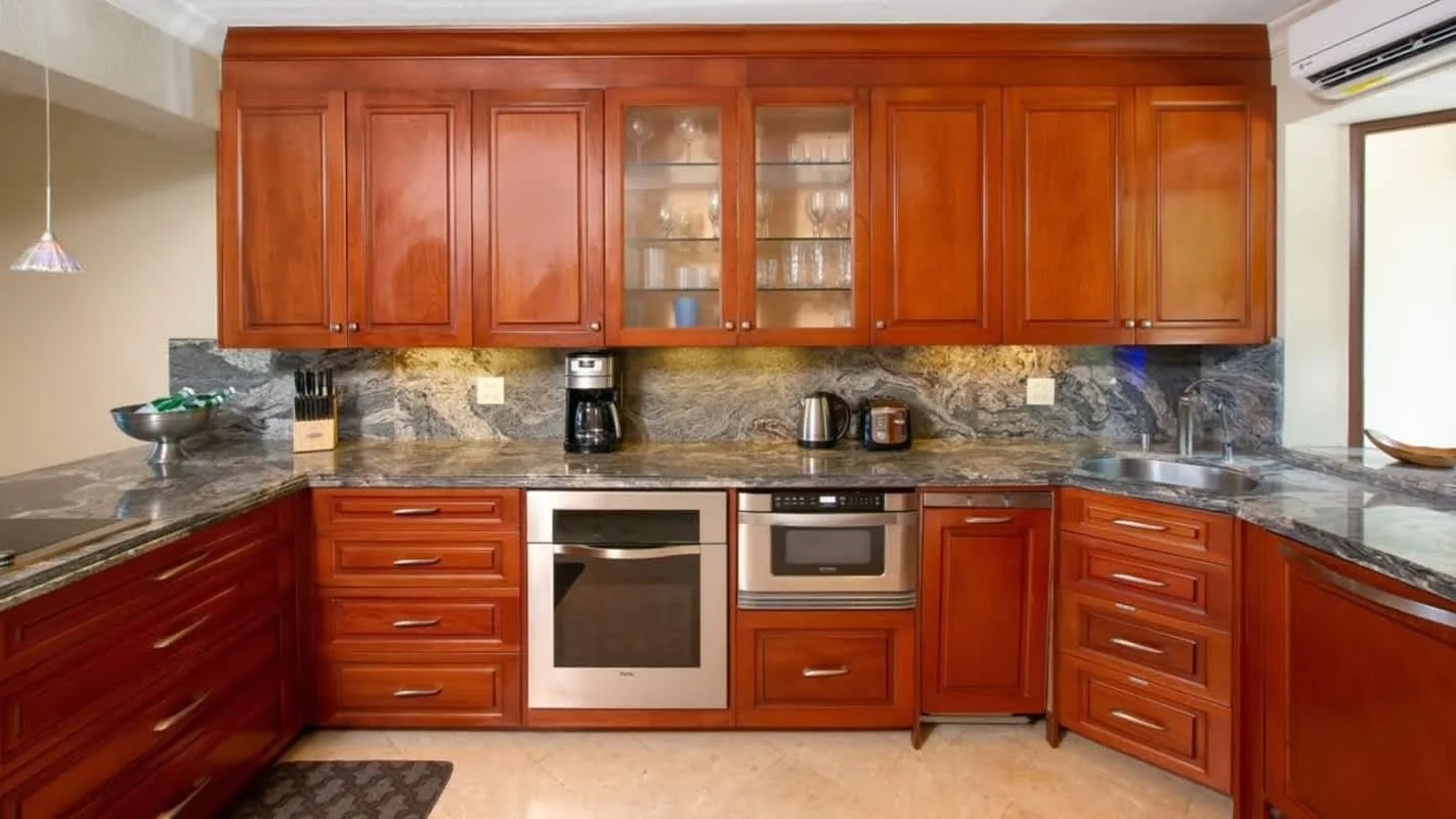 A kitchen with wooden cabinets, stone countertops, and built-in appliances.