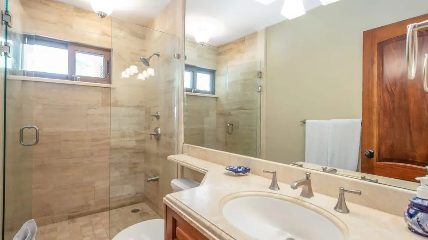 A bathroom with a glass shower, a long vanity, and a wide mirror.