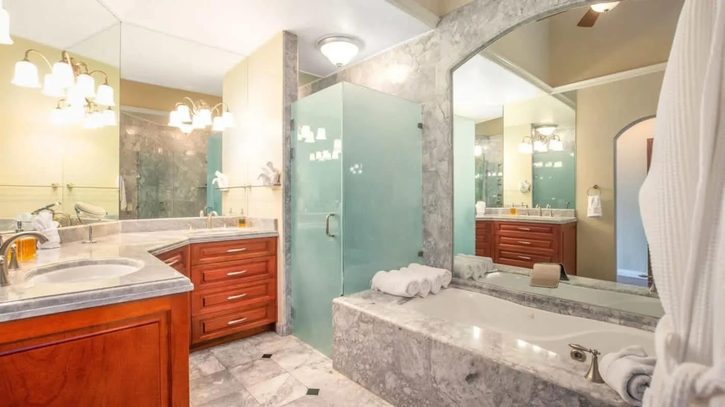 A bathroom with a glass shower, a bathtub, and wood-toned vanities.