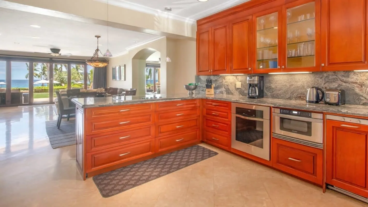 A kitchen with red cabinetry, stone countertops, and appliances.