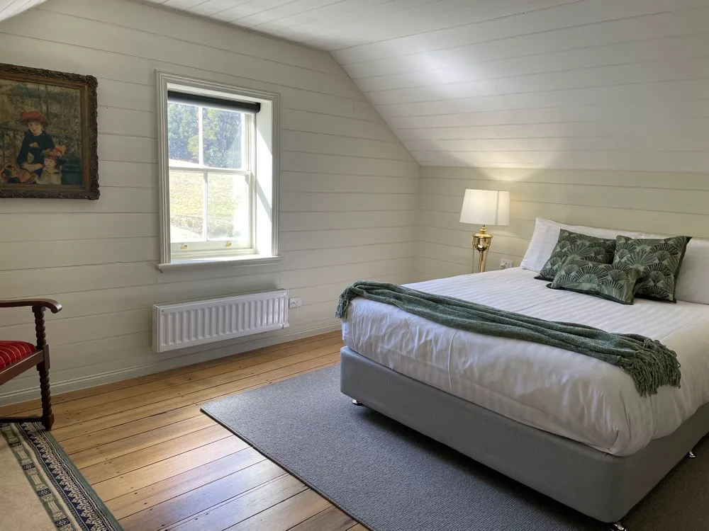A bright bedroom with a bed, a window, and a bedside lamp.
