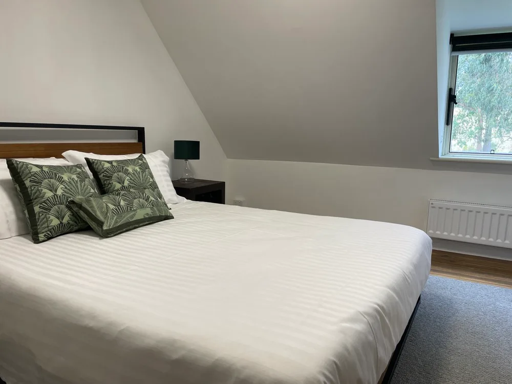 A bedroom with a neatly made bed and a window.