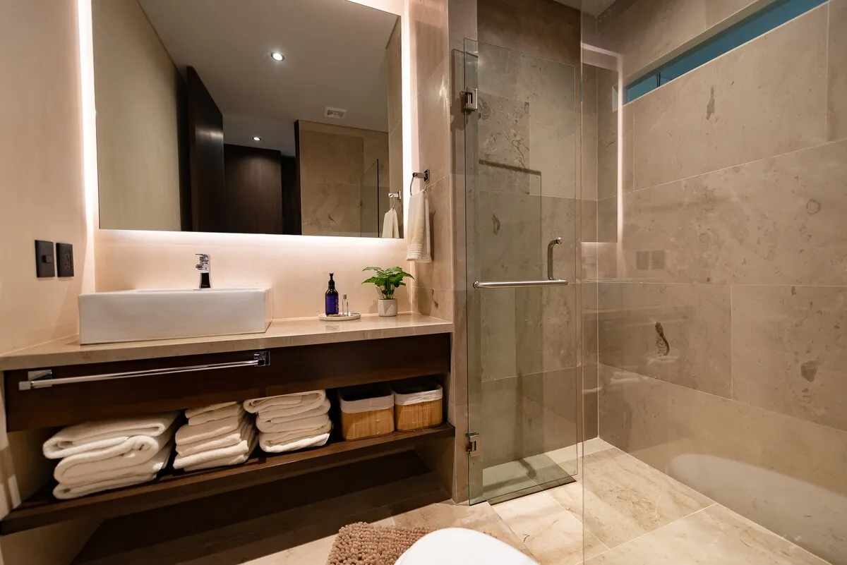 Un baño moderno con un espejo amplio, lavabo y ducha de vidrio.