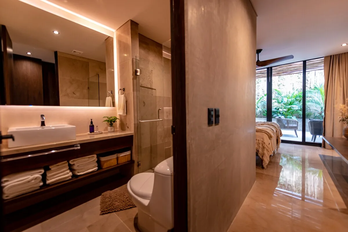 Un dormitorio se abre a un baño con lavabo, ducha e inodoro.