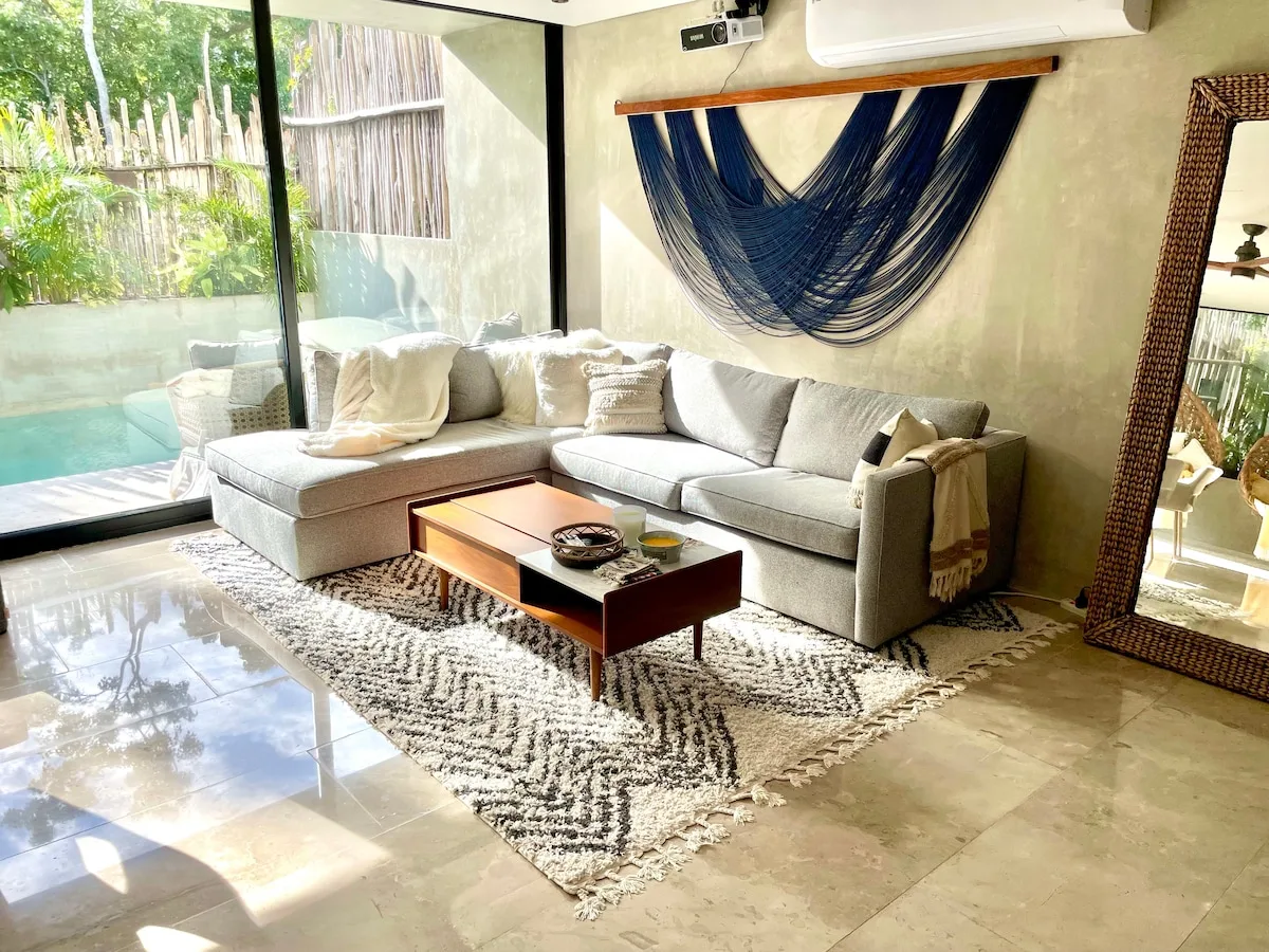 Una sala de estar con asientos, una mesa de centro y una ventana grande.