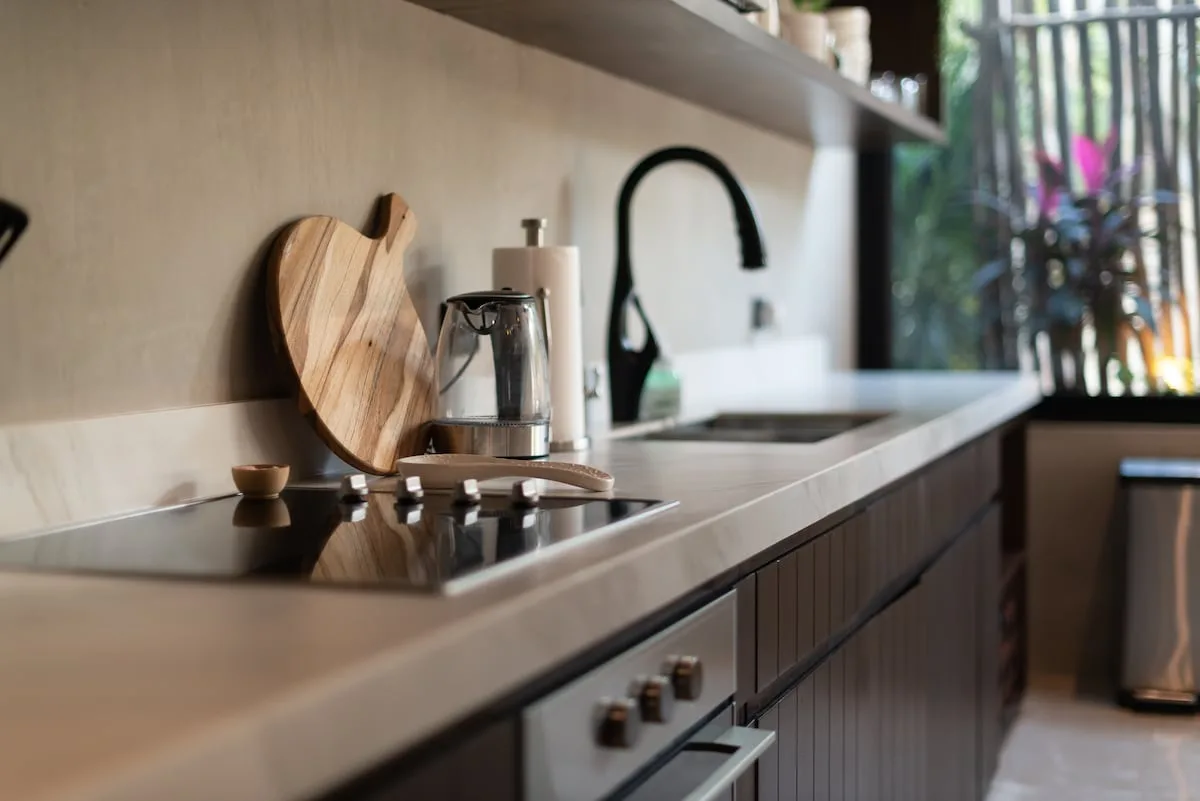 Una cocina moderna con una placa oscura y un fregadero junto a una ventana.