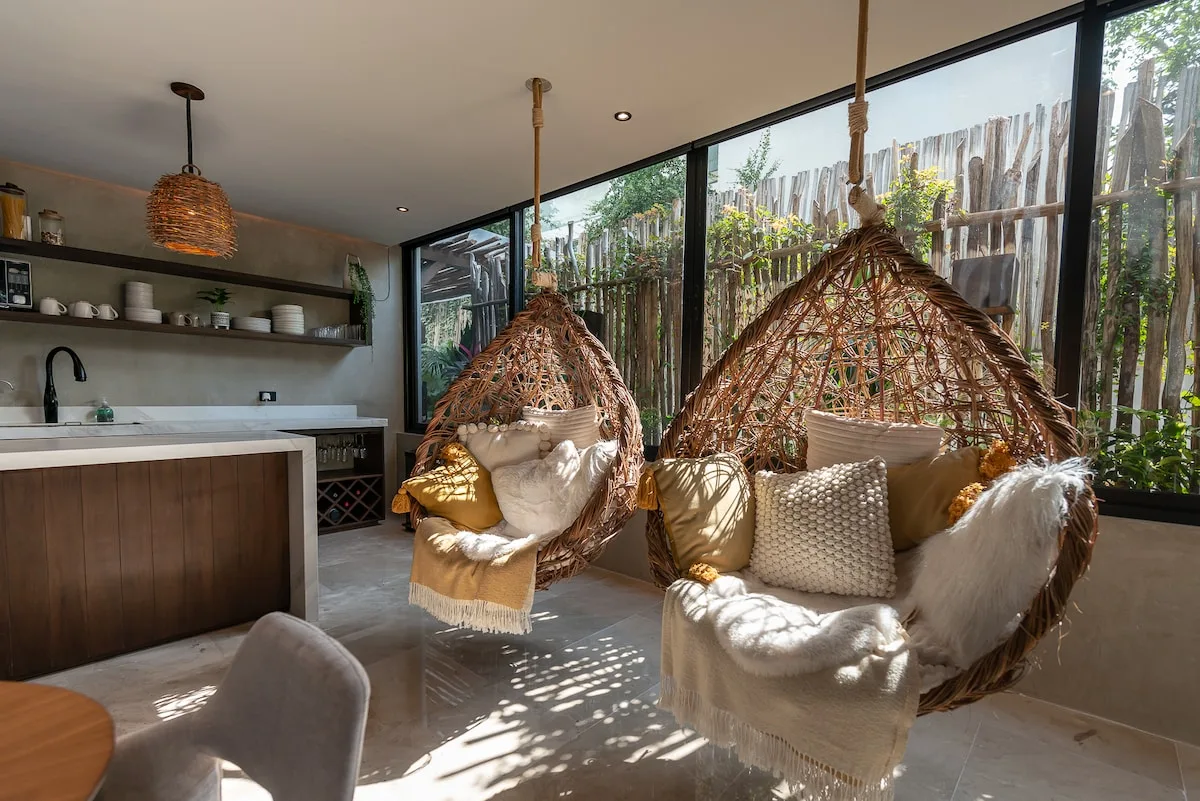 Una sala luminosa con asientos colgantes de tejido junto a una gran ventana.