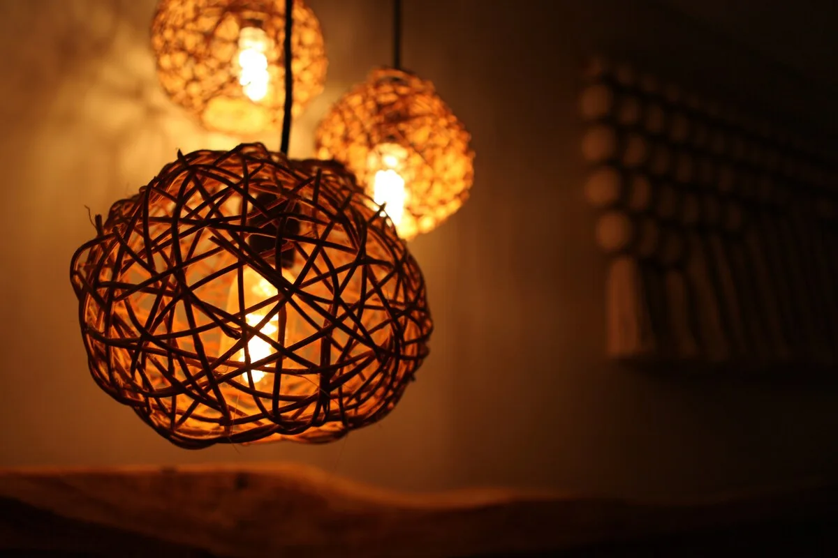 Una habitación cálidamente iluminada tiene lámparas colgantes tejidas sobre una superficie.