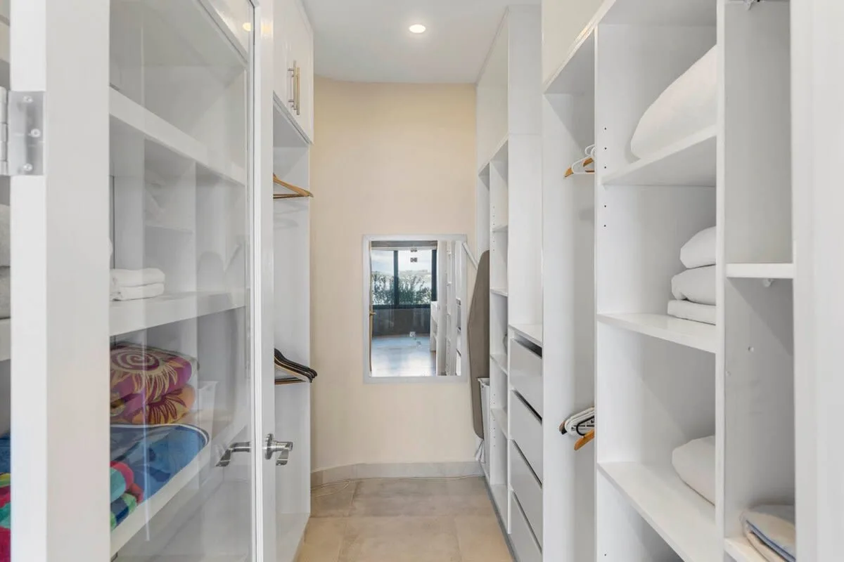 A walk-in closet with open shelving and folded linens.