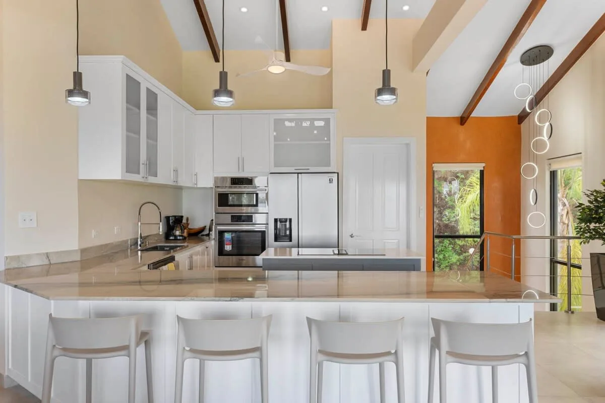 A bright kitchen with white cabinetry, a central island, and stools.