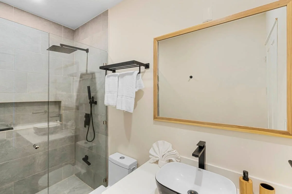 A modern bathroom with a glass shower and a white sink.