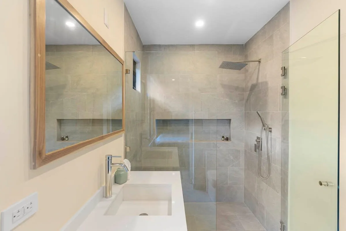 A tiled bathroom with a glass shower and a sink.
