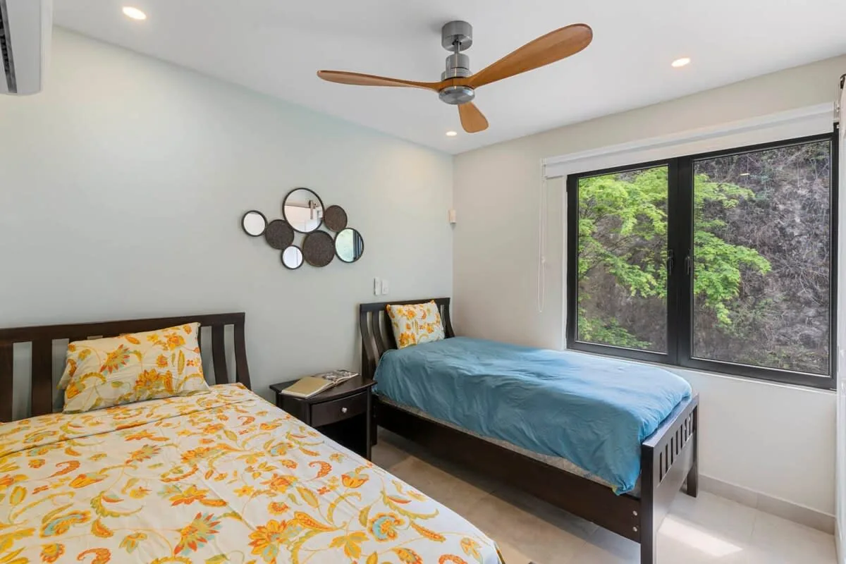 A bedroom with two beds, including one covered in blue bedding.