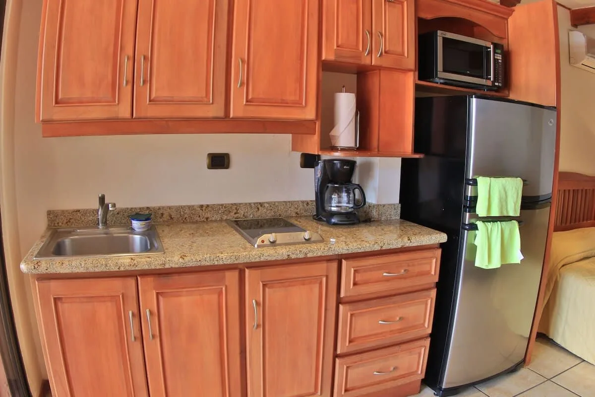 A compact kitchen with wooden cabinets, a countertop, and a refrigerator.