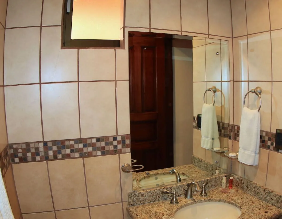 A tiled bathroom with a large mirror above the sink.